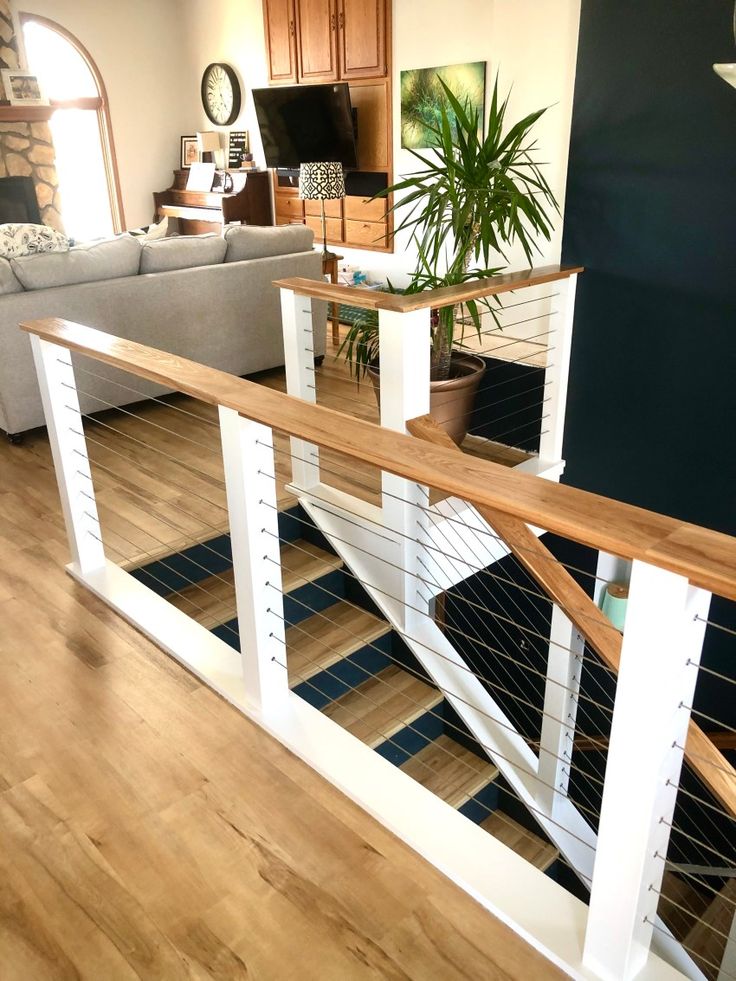 a living room filled with furniture next to a wooden floor and white stair railings