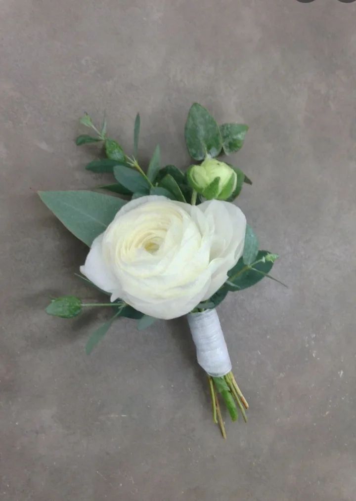 a bridal bouquet with white flowers and green leaves on the side of a concrete floor