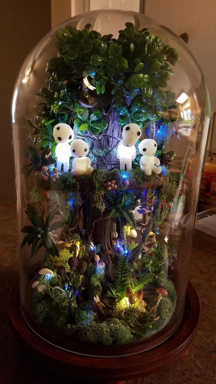 a glass dome filled with lots of plants and stuffed animals on top of it's sides