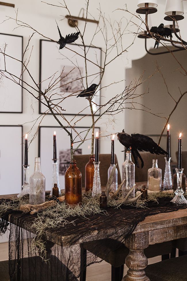 a table topped with lots of bottles filled with candles and birds flying over the top