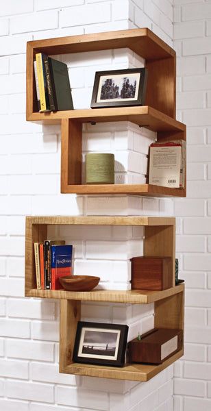 three wooden shelves with books on them against a white brick wall in the corner of a room