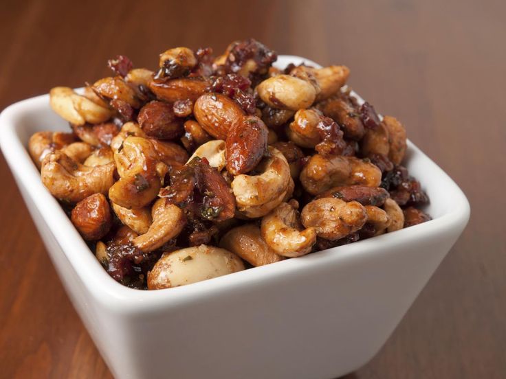 a white bowl filled with nuts on top of a wooden table