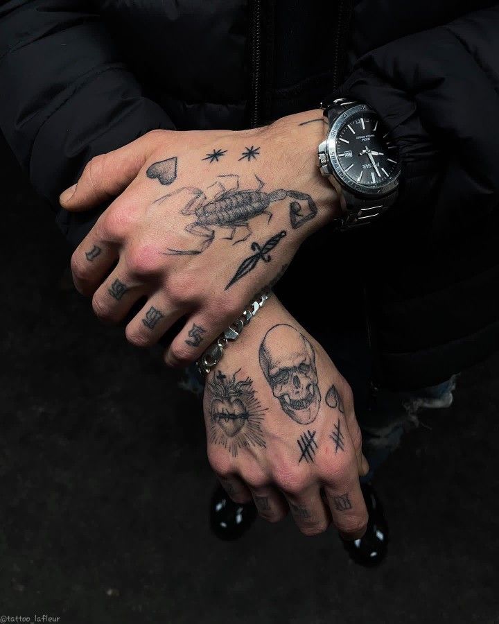 two hands with tattoos on them, one has a watch and the other has a skull