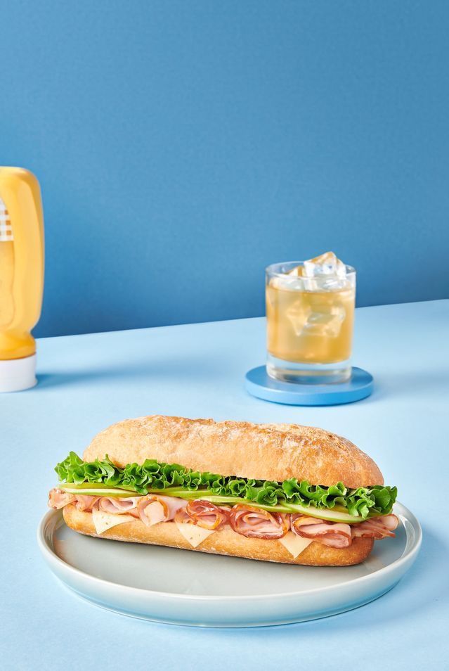 a sub sandwich sitting on top of a plate next to a glass of lemonade