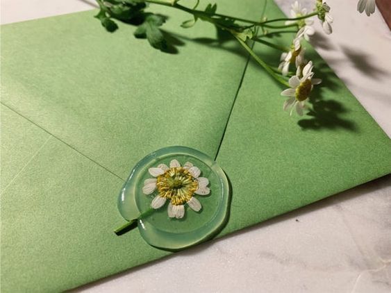 a green envelope with a flower in the center and some white flowers on it,