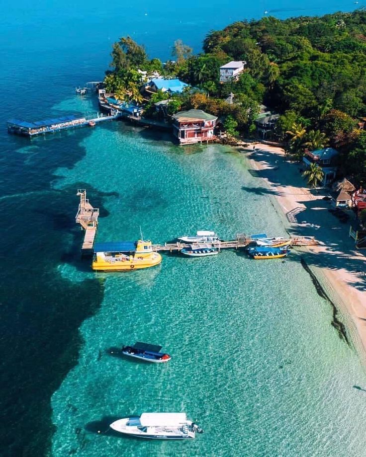 an island with several boats in the water and some houses on land next to it