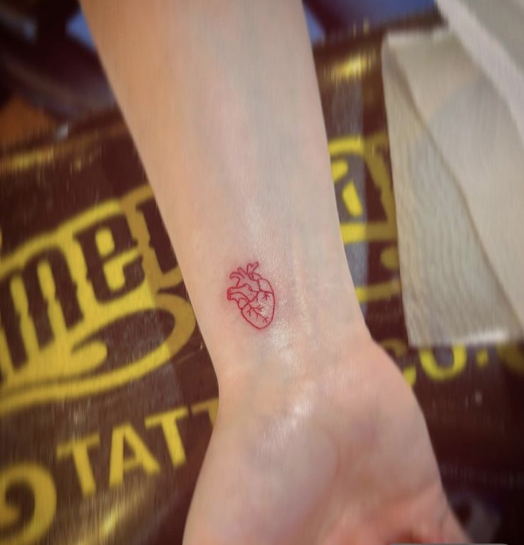 a small red heart tattoo on the wrist