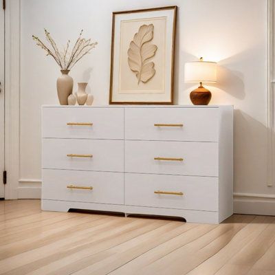 a white dresser with two vases and a painting on the wall next to it