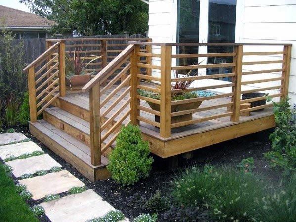 a wooden deck with planters on it and steps leading to the back yard area