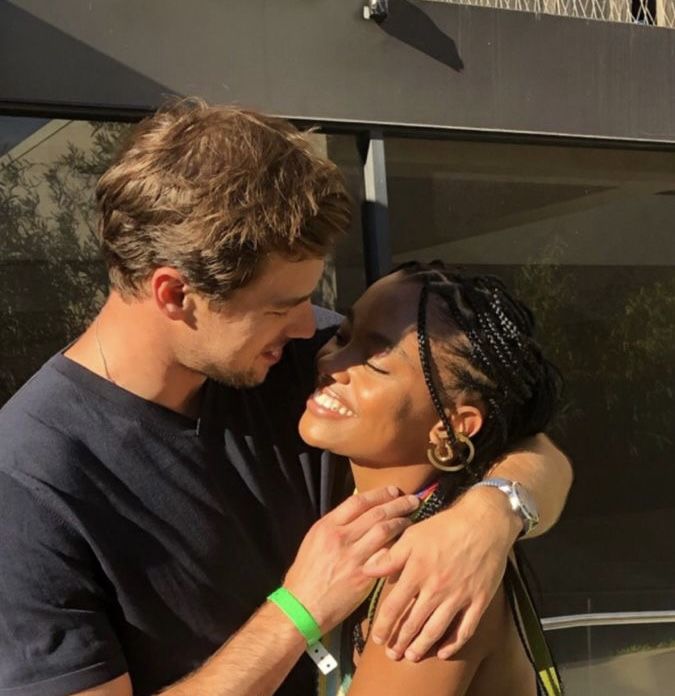 a man and woman embracing each other in front of a building with the sun shining on them