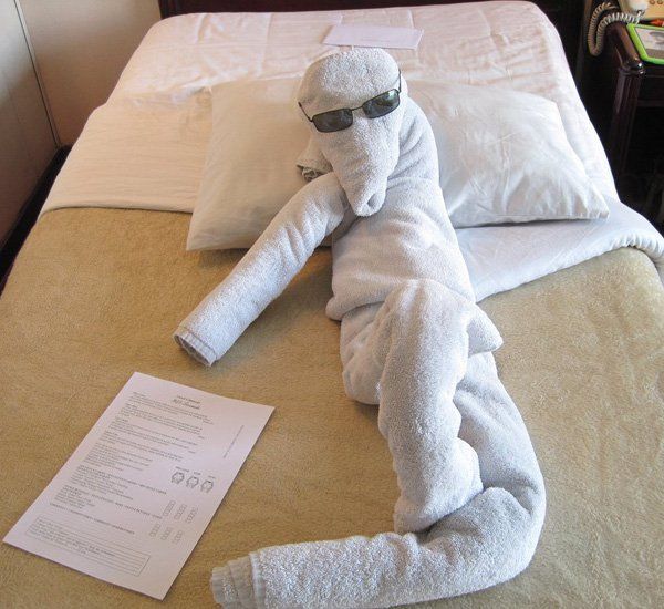 a towel animal laying on top of a bed next to a piece of white paper