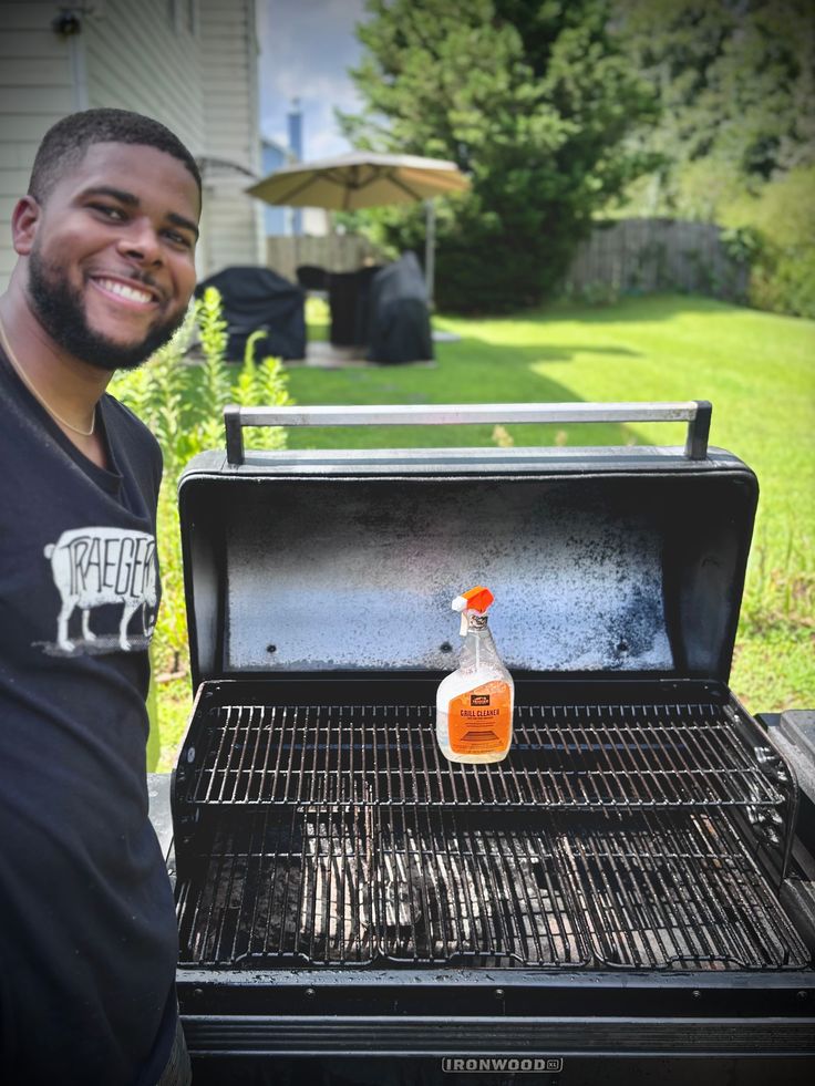 a man standing in front of an open grill with a bottle of liquid on it