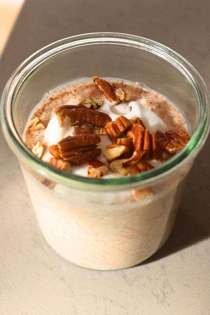 a glass jar filled with yogurt and pecans