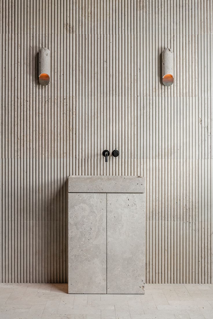 two concrete sinks in front of a wall with vertical stripes