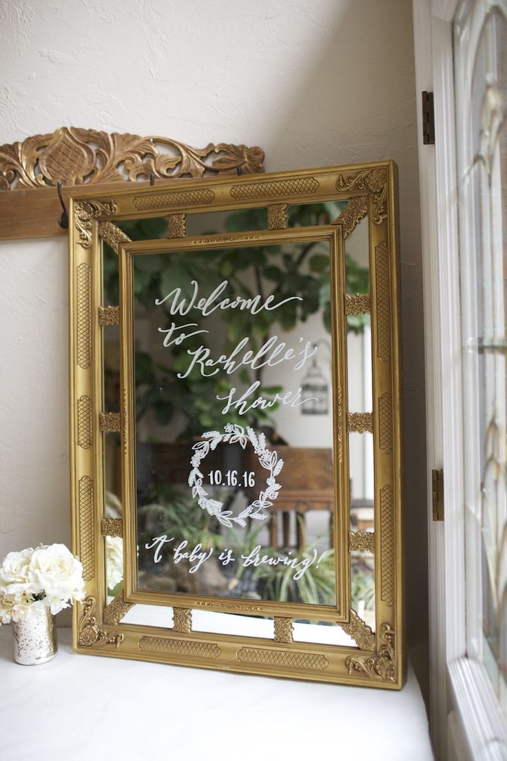 a gold framed mirror sitting on top of a white table next to a vase with flowers