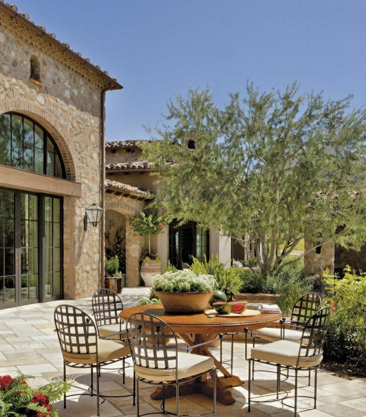 an outdoor dining table with four chairs and a potted plant in front of it