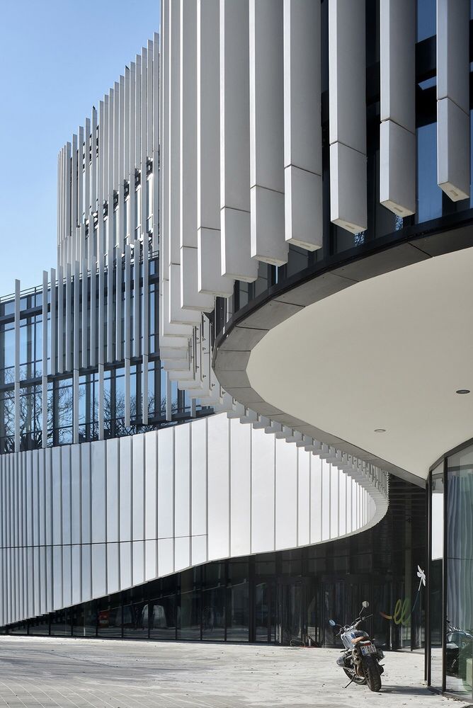 a motorcycle parked in front of a building with curved walls and glass windows on the side