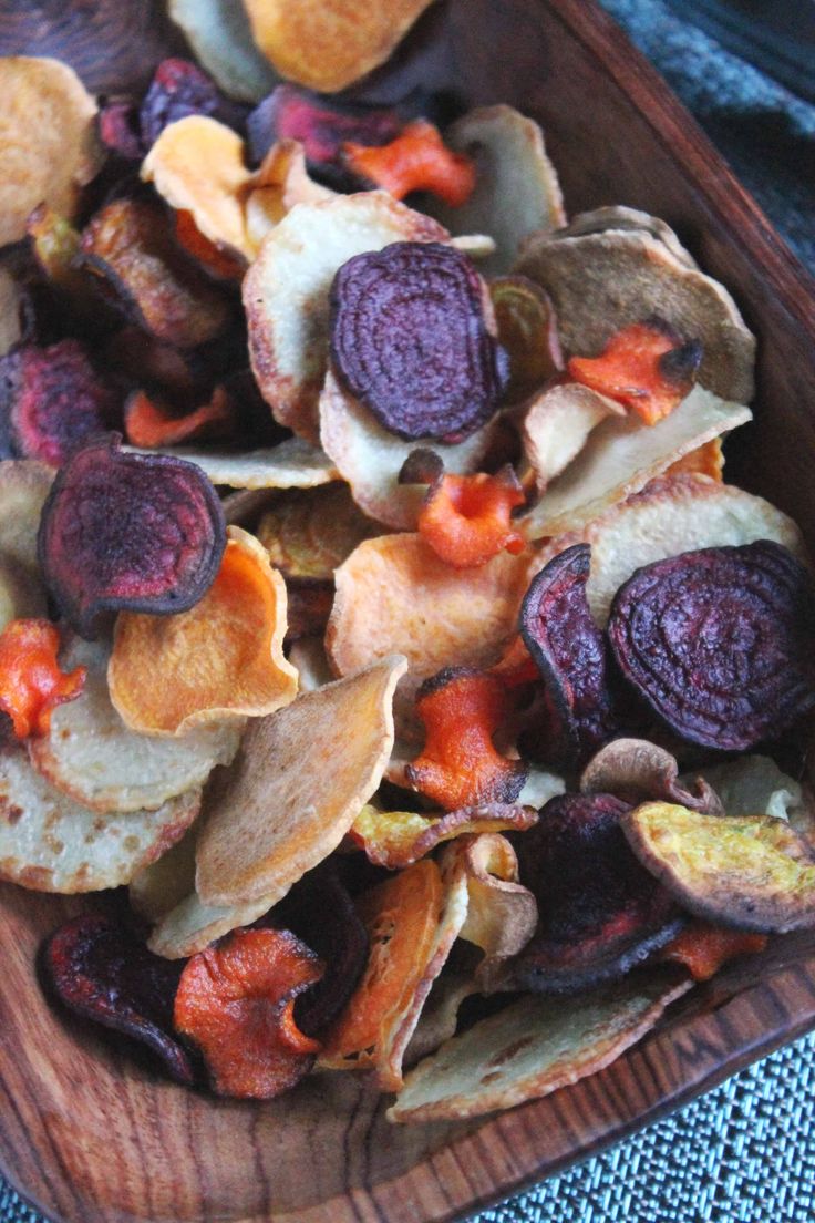 a wooden bowl filled with potato chips and carrots