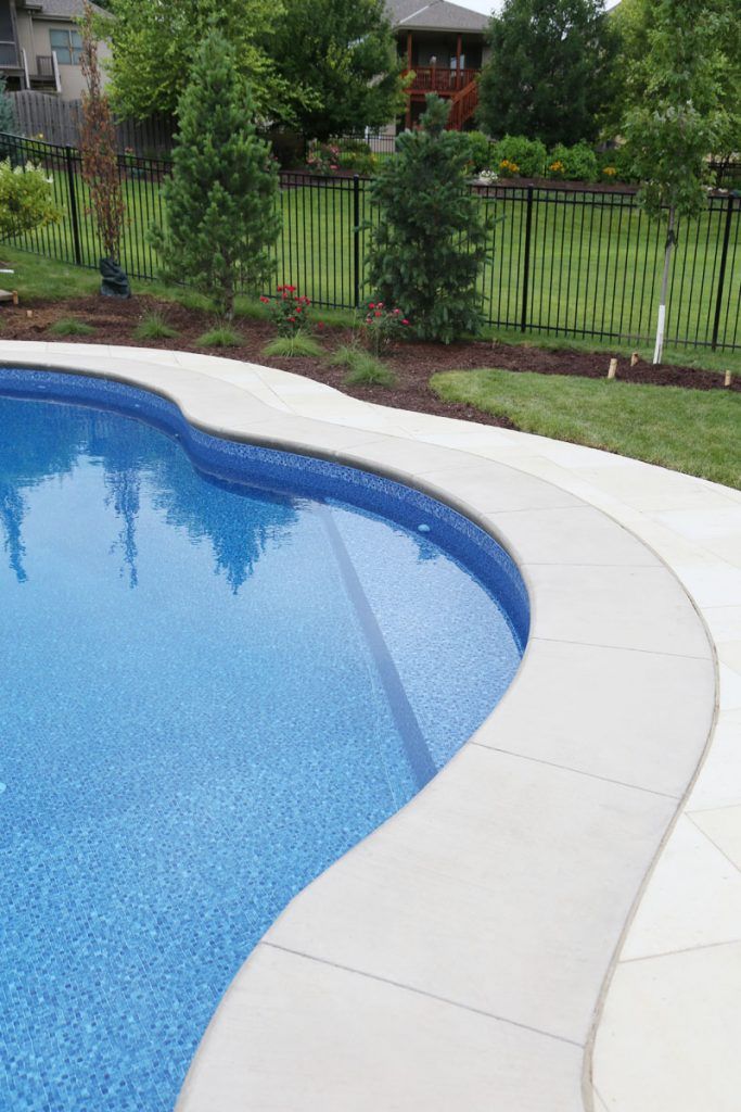 an empty swimming pool in the middle of a yard with fenced in area around it