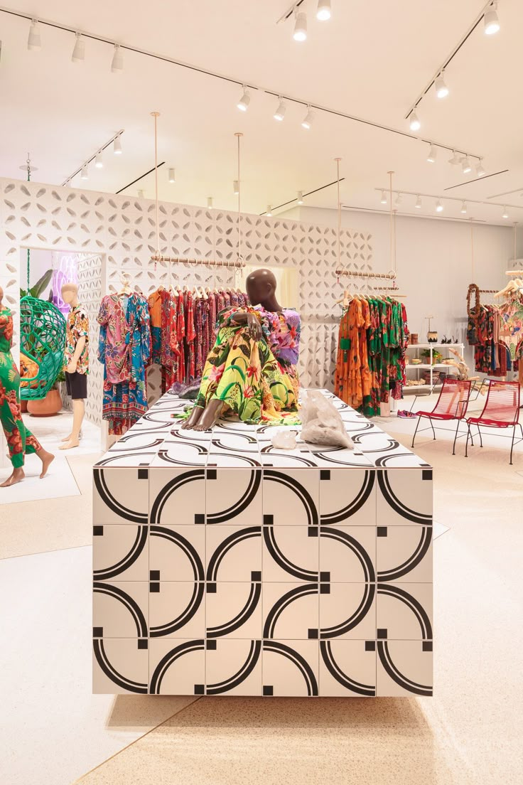 a woman sitting on top of a table in front of a display case filled with clothes