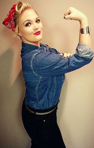 a woman wearing a denim shirt and red bandanna standing in front of a wall