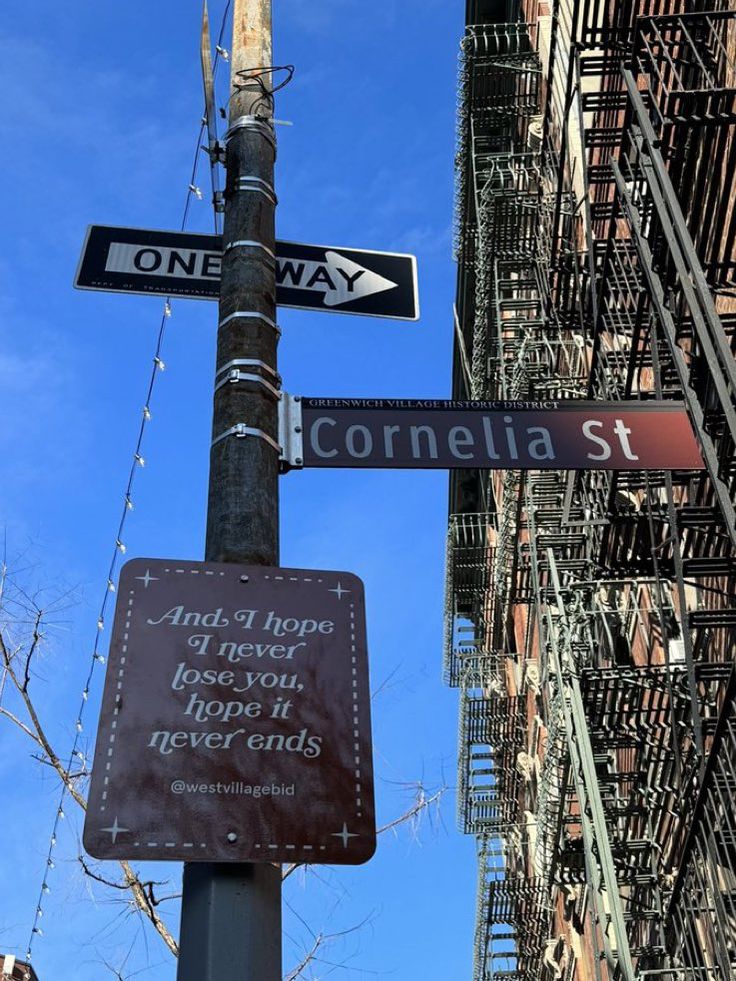 two street signs are attached to a pole in front of apartment buildings on the corner of cornelia st and third avenue