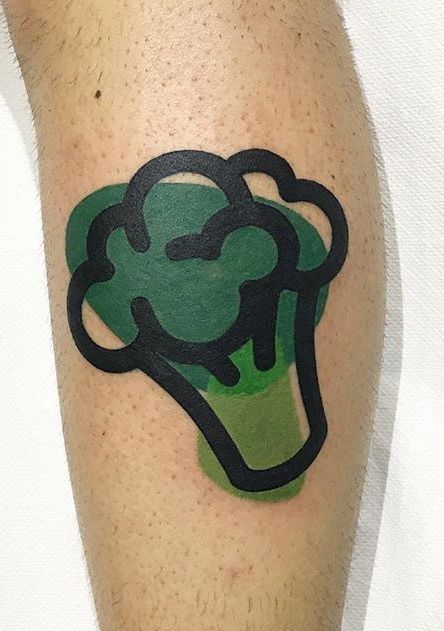 a tattoo on the leg of a man with a green cupcake in it's center