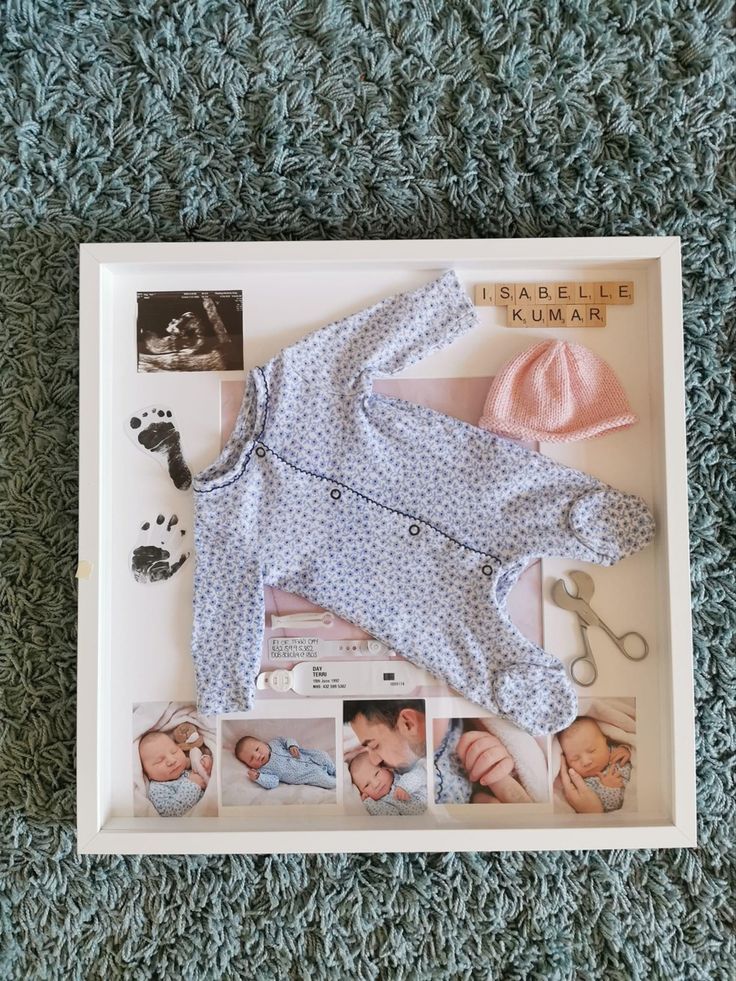 a baby's clothes and accessories laid out in a shadow box on the floor