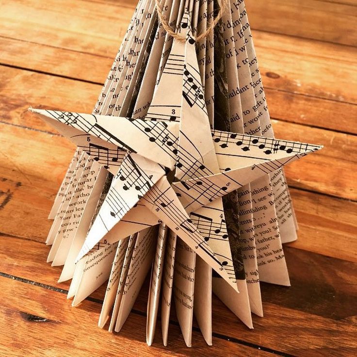 an origami christmas tree made out of sheet music notes is displayed on a wooden table