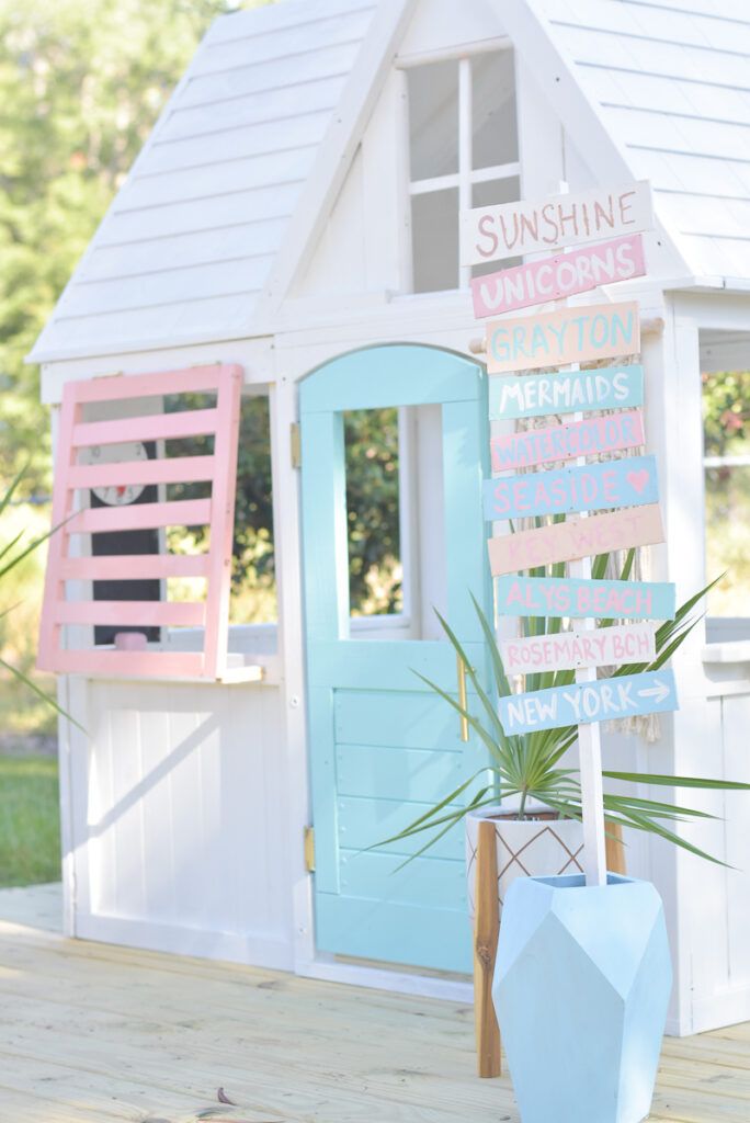 a small white house with a blue door and pink windows