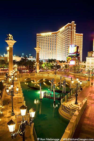 the las vegas hotel and casino is lit up at night with lights reflecting in the water