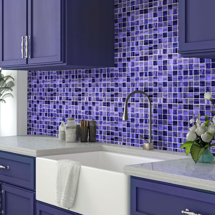 a kitchen with blue cabinets and tile backsplash, white countertops and sink