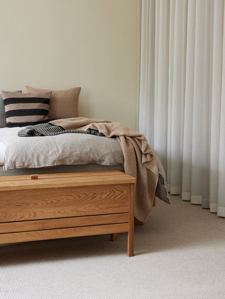 a bed sitting in a bedroom next to a window with white drapes on it