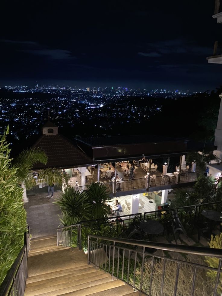 stairs leading up to the top of a building at night with city lights in the background