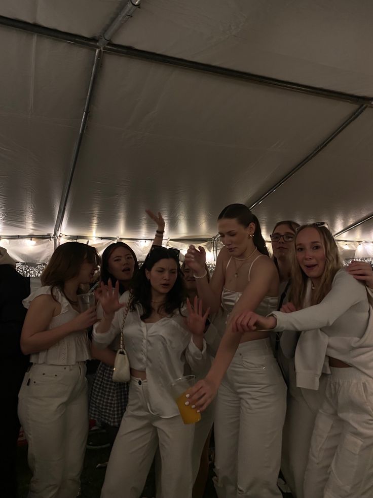 a group of women standing next to each other under a tent