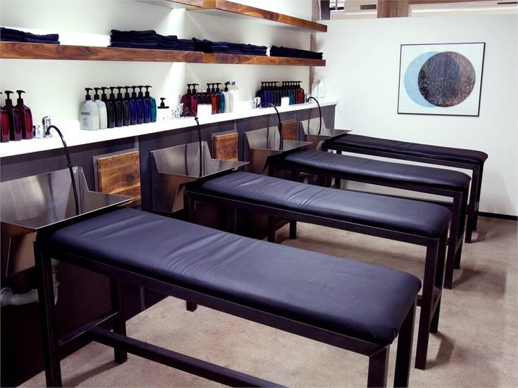 a row of black benches sitting next to each other in front of a wall filled with bottles