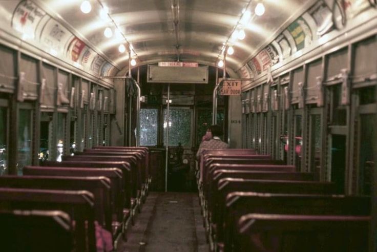 the inside of a train car with rows of empty seats and lights on either side