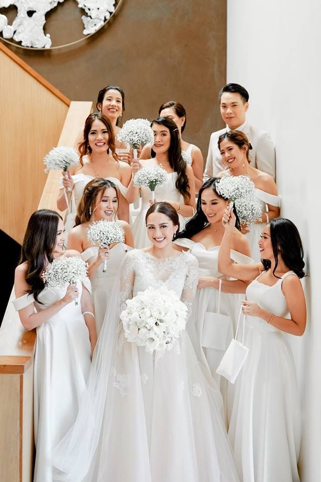 a group of women standing next to each other in front of a staircase holding bouquets