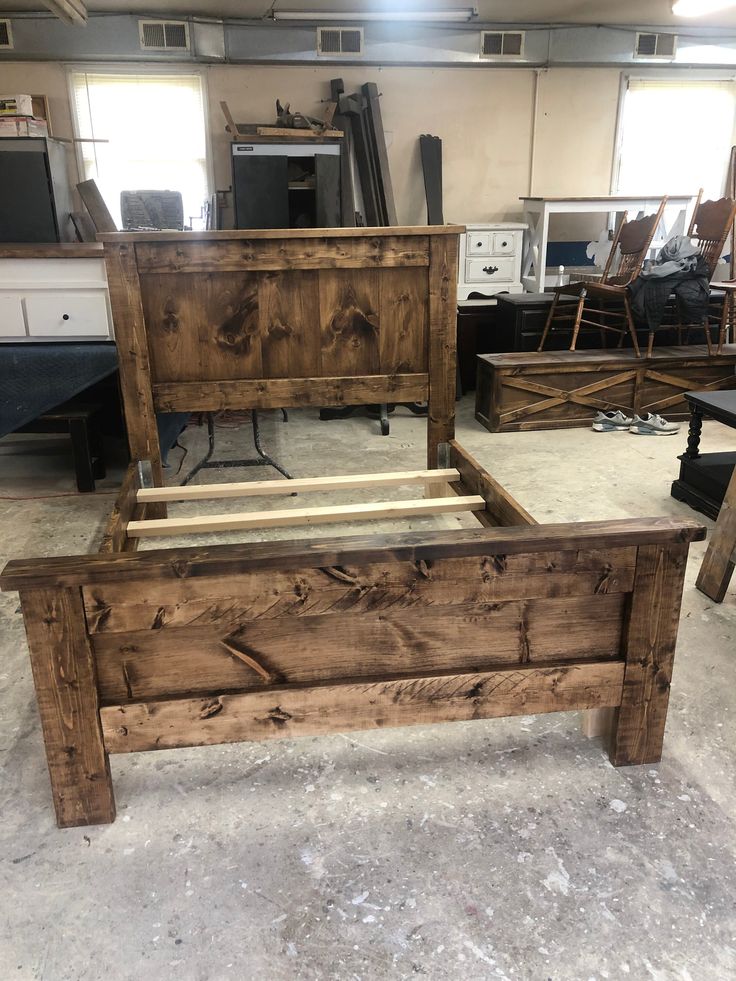 a bed frame made out of wood sitting in a room with other furniture and tools