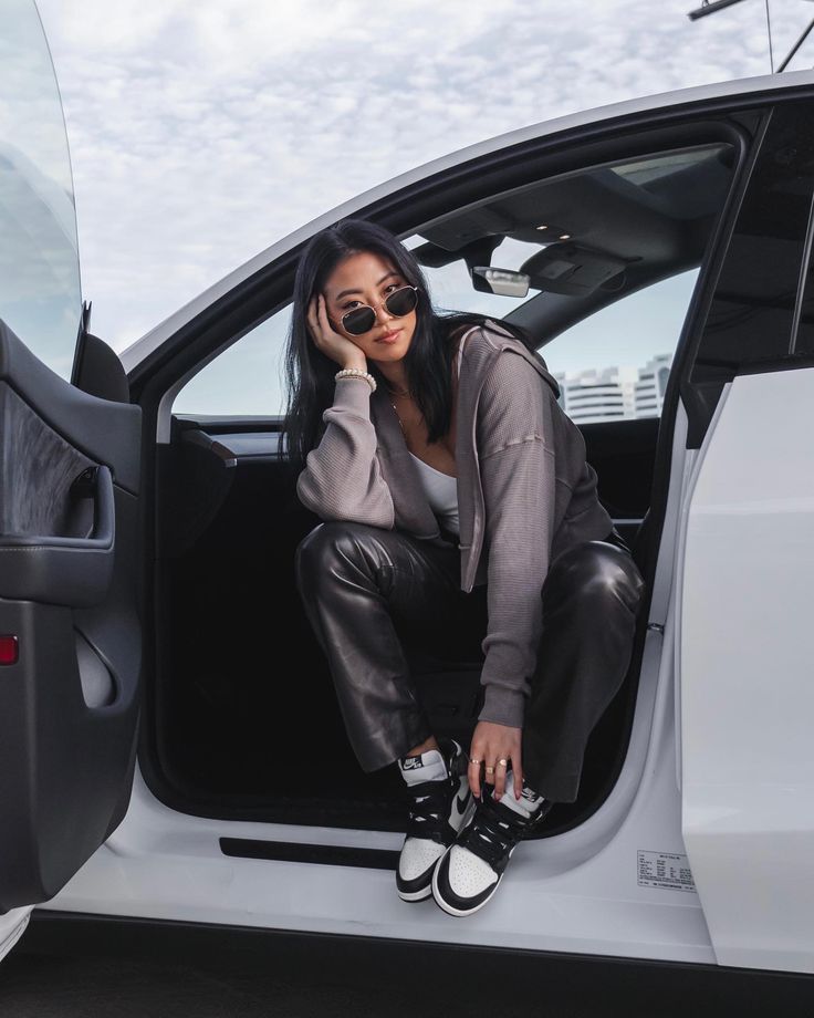 a woman sitting in the driver's seat of a car with her hand on her face