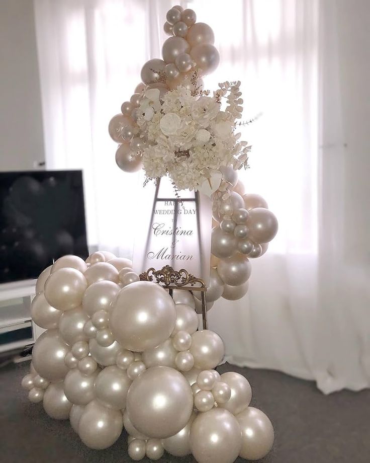 a bunch of balloons that are in the shape of a tower with flowers on top