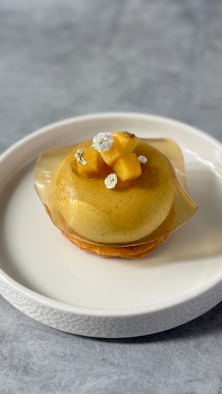 a small dessert on a white plate with sauce and flowers in the middle, ready to be eaten