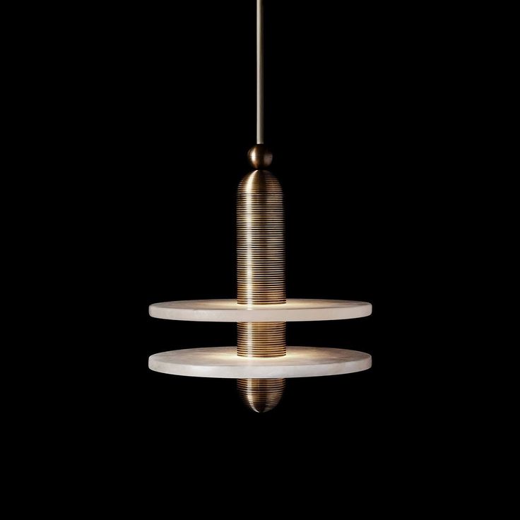 a modern light fixture hanging from the ceiling in a dark room with three plates stacked on top of each other