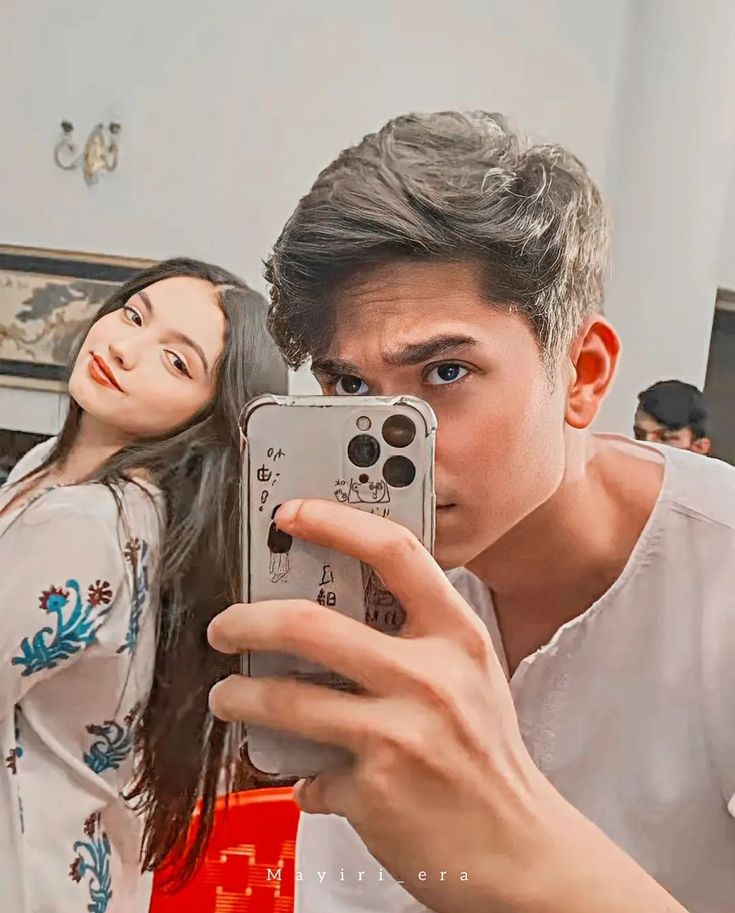 a man and woman taking a selfie in front of a mirror with their cell phone