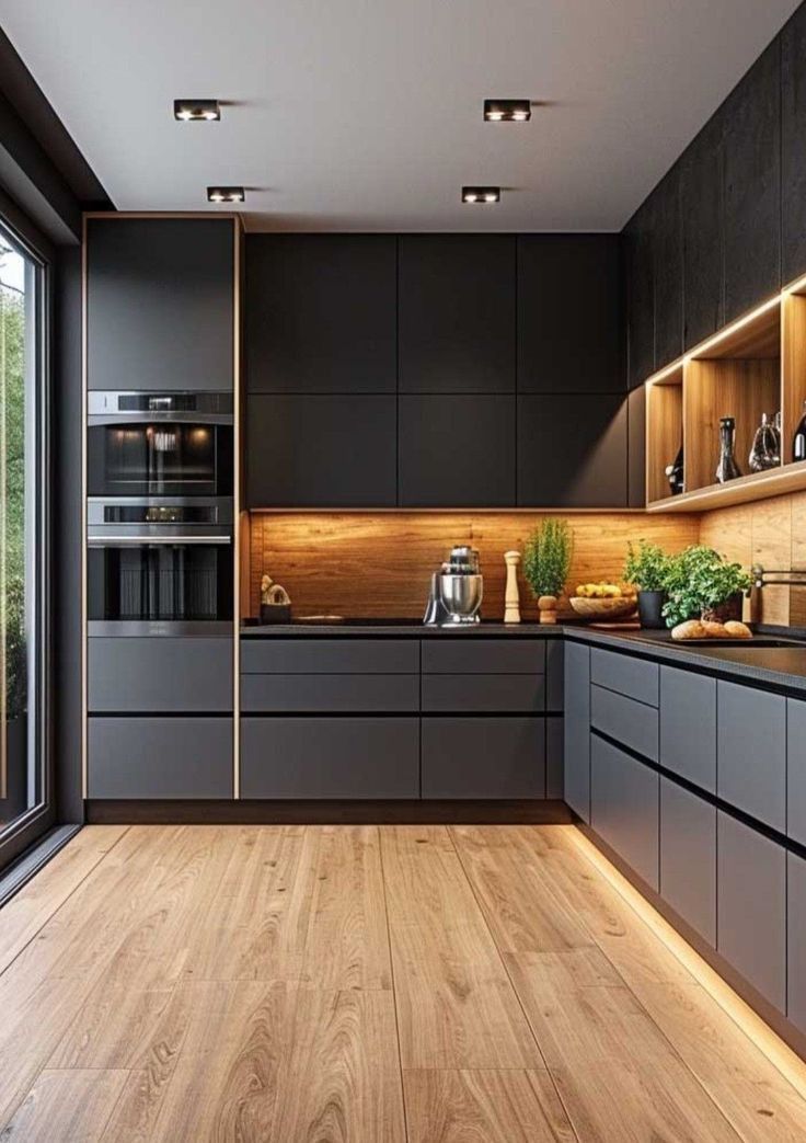 a modern kitchen with wood flooring and black cabinets is lit by recessed lighting