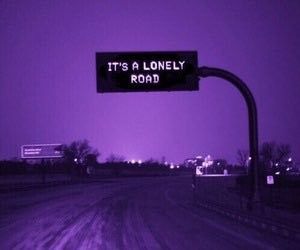 a street sign that says it's a lonely road in front of a purple sky