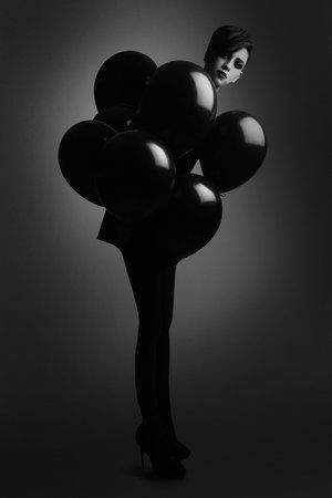 black and white photograph of a woman with balloons in her hand, wearing high heels