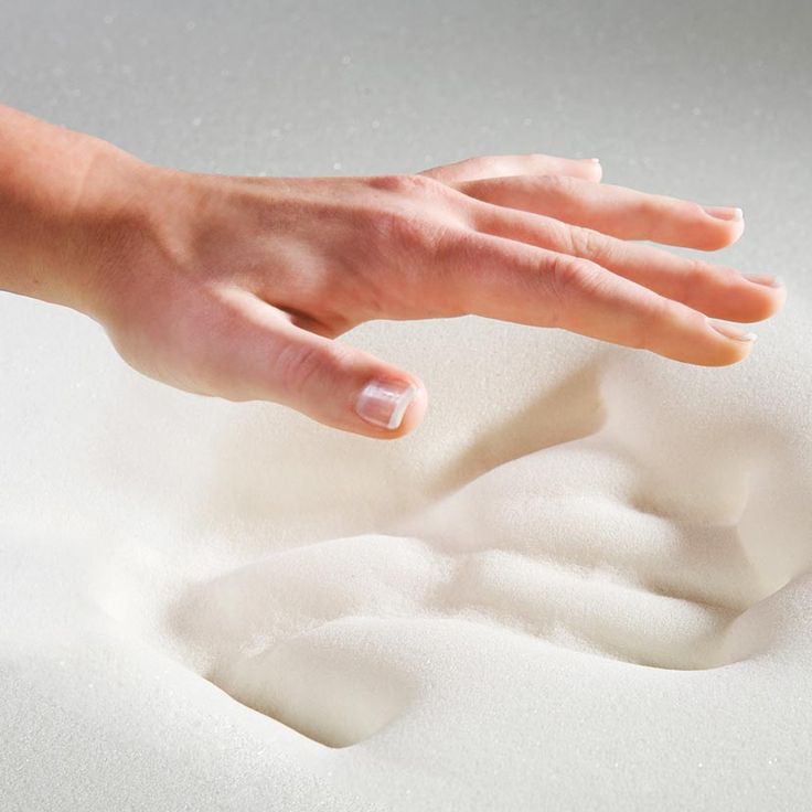 a person's hand reaching for the foam on top of a white bed sheet