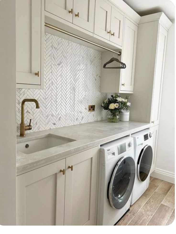 a washer and dryer in a white kitchen with herringbone backsplash