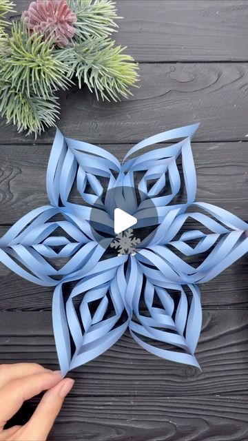 someone is making an origami flower out of blue paper